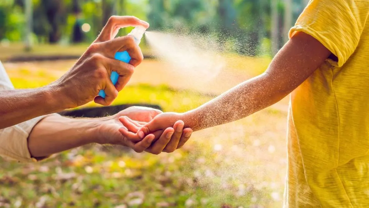 Flacon de répulsif anti-moustique posé sur une table de jardin avec moustique en gros plan sur le bras