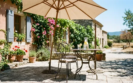 Terrasse française paisible en pleine canicule d'été avec parasol et carafe d'eau fraîche, ambiance ensoleillée sans moustiques visibles, style éditorial magazine