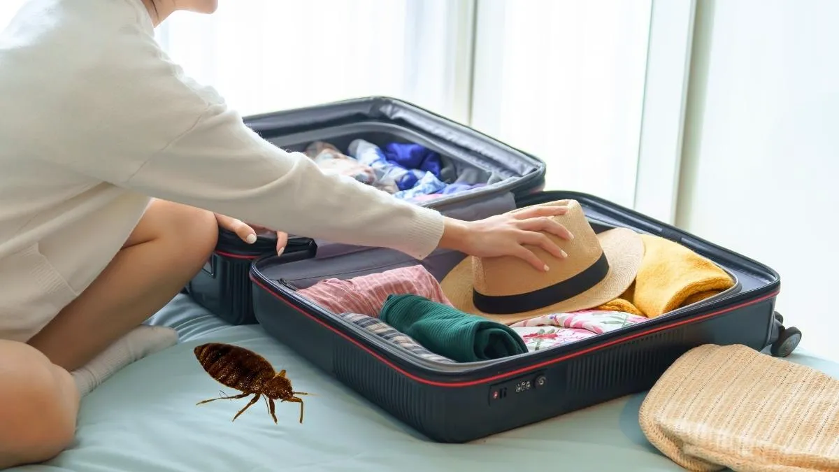 Valise rouge ouverte sur un lit d'hôtel avec vêtements pliés et housse de matelas blanche visible en arrière-plan