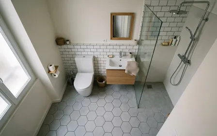 Salle de bain française contemporaine avec cuvette de toilettes fermée en céramique blanche et sol carrelé gris clair vu de dessus, ambiance sobre lumière naturelle douce du matin aucun humain visible plan large documentaire