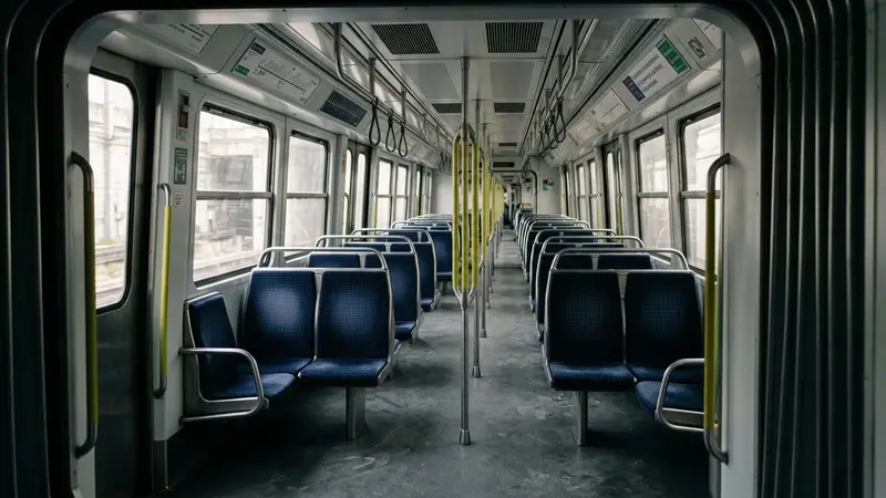 Rame de métro parisien contemporain avec sièges en tissu bleu alignés et fenêtres carrées vue depuis l'entrée du wagon, ambiance sobre lumière naturelle documentaire aucun humain visible plan large