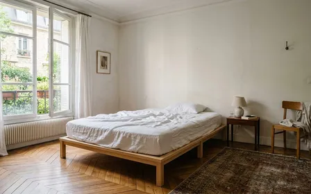 Chambre française contemporaine vide avec matelas nu recouvert d'un drap blanc et sommier en bois clair vus de face, ambiance sobre lumière naturelle douce de fin de matinée aucun humain visible plan large documentaire
