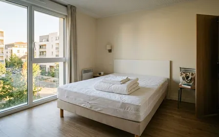 Chambre française d'immeuble contemporain avec draps blancs pliés et housse anti-punaises hermétique posée sur un matelas isolé du mur en début de matinée de septembre, ambiance sobre lumière naturelle documentaire aucun humain visible plan large