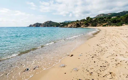 Plage méditerranéenne française du littoral azuréen en fin de matinée de septembre avec sable clair et eau calme aux nuances turquoise et petits débris de méduse translucides au bord de l'eau, ambiance sobre lumière naturelle documentaire aucun humain visible plan large