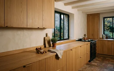 Cuisine française contemporaine avec placard fermé et plan de travail en bois clair dégagé en début de soirée d'automne, ambiance sobre lumière naturelle documentaire aucun humain ni insecte visible plan large horizontal