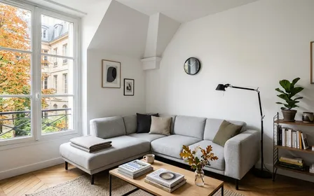 Coin de salon français contemporain avec canapé en tissu gris clair et angle de plafond propre avec peinture blanche en début d'après-midi d'automne, ambiance sobre lumière naturelle documentaire aucun humain ni araignée visible plan large horizontal