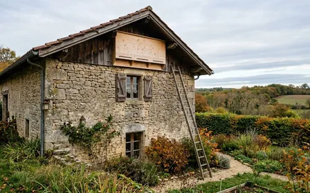 Gîte en bois non traité pour chauves-souris pipistrelles fixé en hauteur sur la façade sud d'une maison française, avec ouverture étroite inférieure et vue sur un jardin arboré automnal